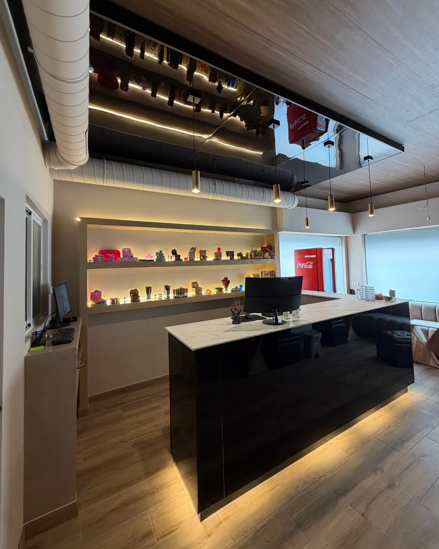 The bar at Velvet: black gloss counter with marble top, brass pendant lights and a mirrored ceiling